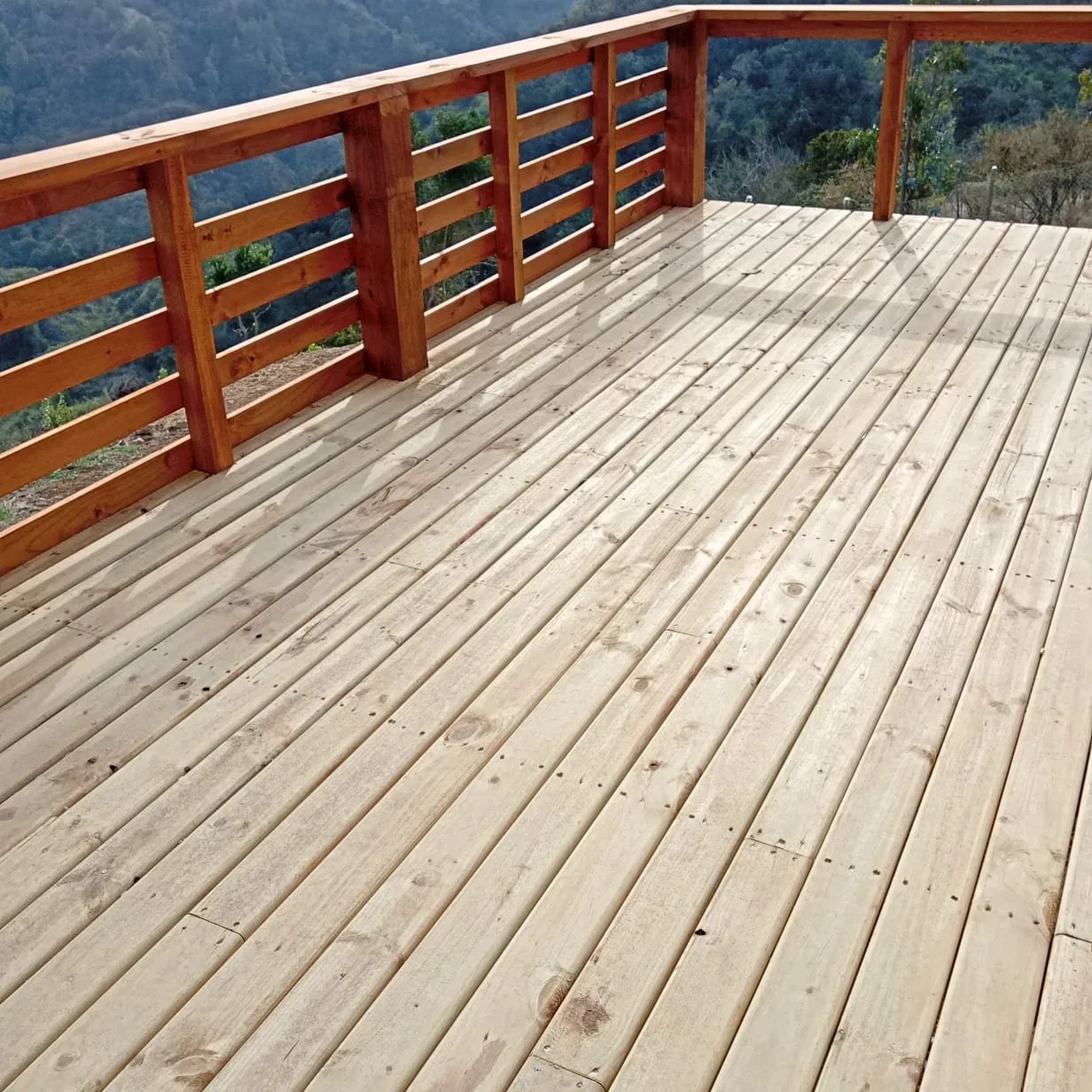 Terraza de madera con baranda y vista a los cerros